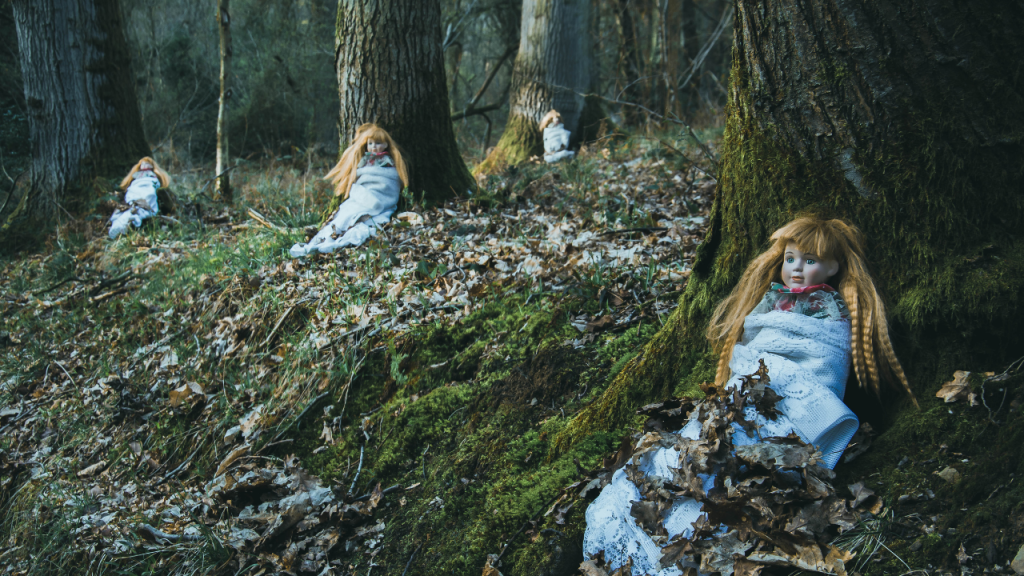 Puppen im Wald lehnen an Bäumen