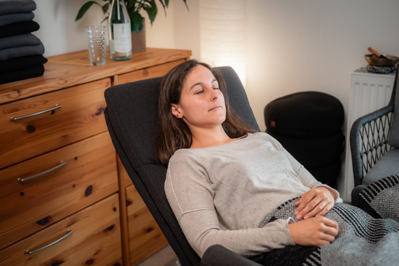 Junge Frau (Klientin) liegt mit geschlossenen Augen entspannt auf einem Relaxsessel.