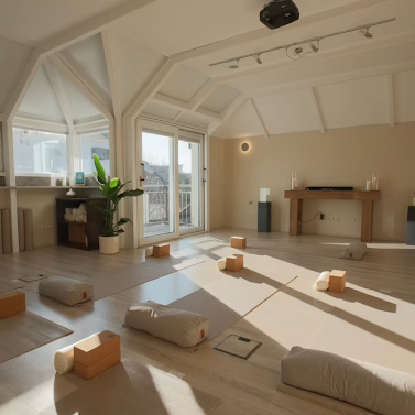 Momentum360 Rosenheim Gruppenraum mit Yogamatten und Kissen, Kerzen und Pflanzen im Hintergrund