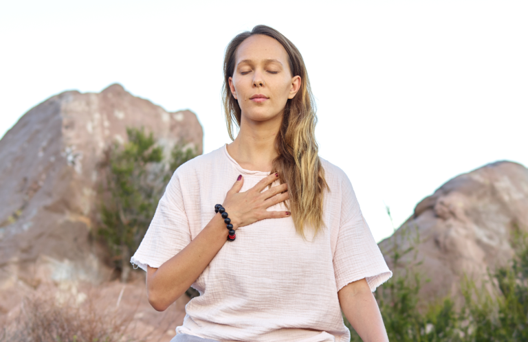Tara Brach Meditation RAIN Achtsamkeit Mindfulness Emotional Release junge Frau meditiert mit geschlossenen Augen, hat eine Hand auf die Brust gelegt.
